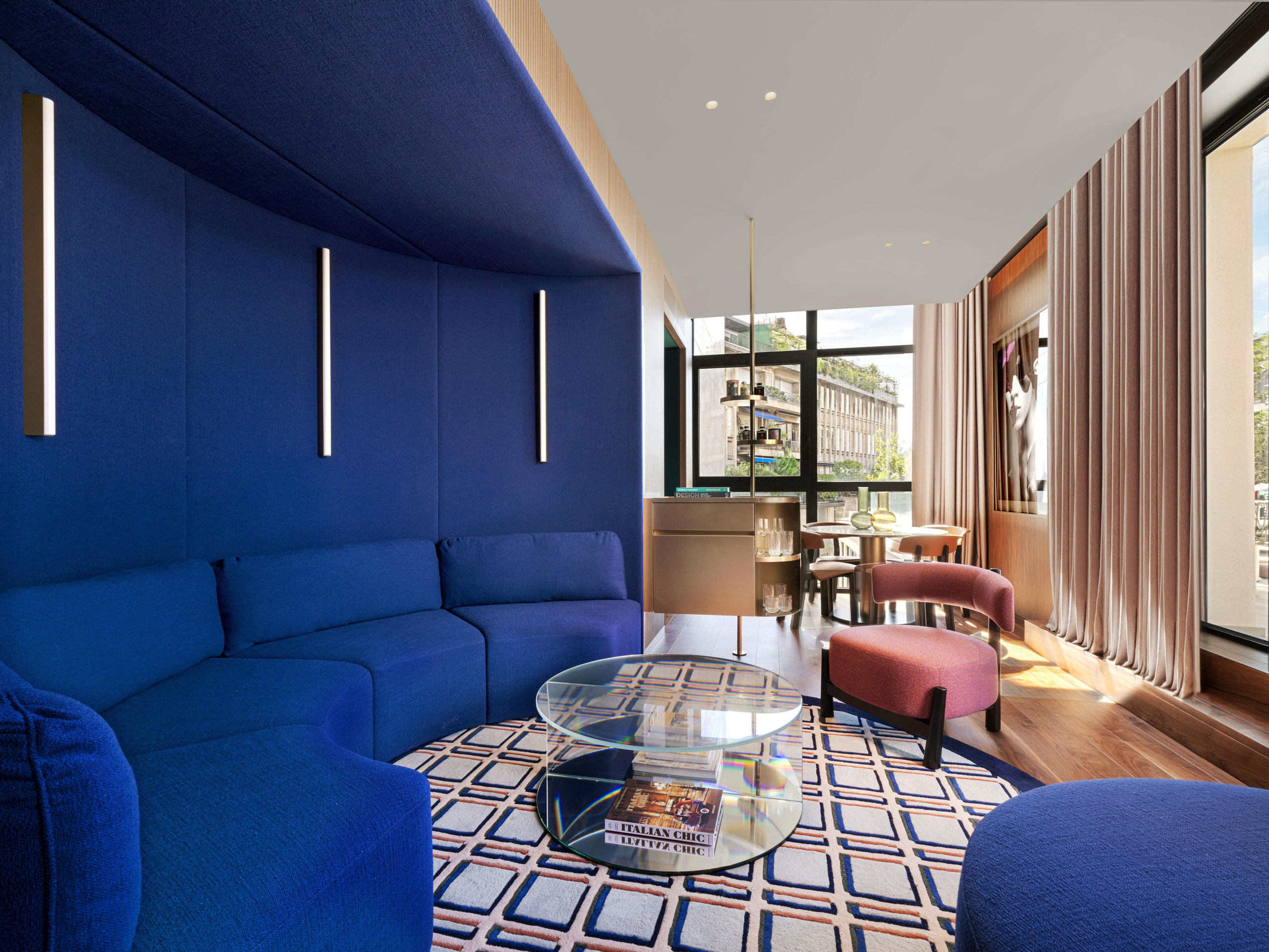 Hotel lounge with deep blue velvet seating and floor-length curtains