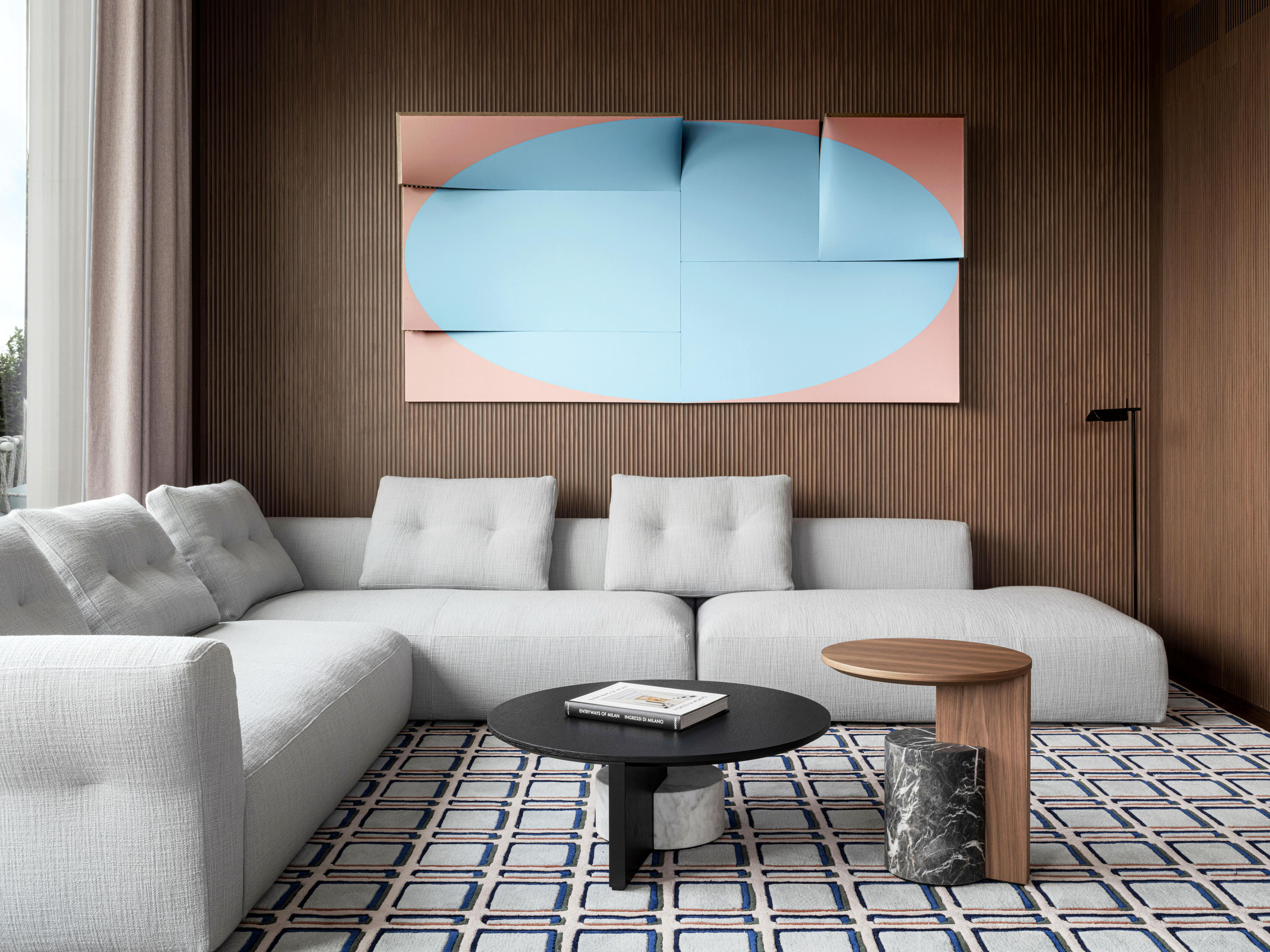 Suite living room with a pale sectional sofa and abstract artwork on a wood-panelled wall