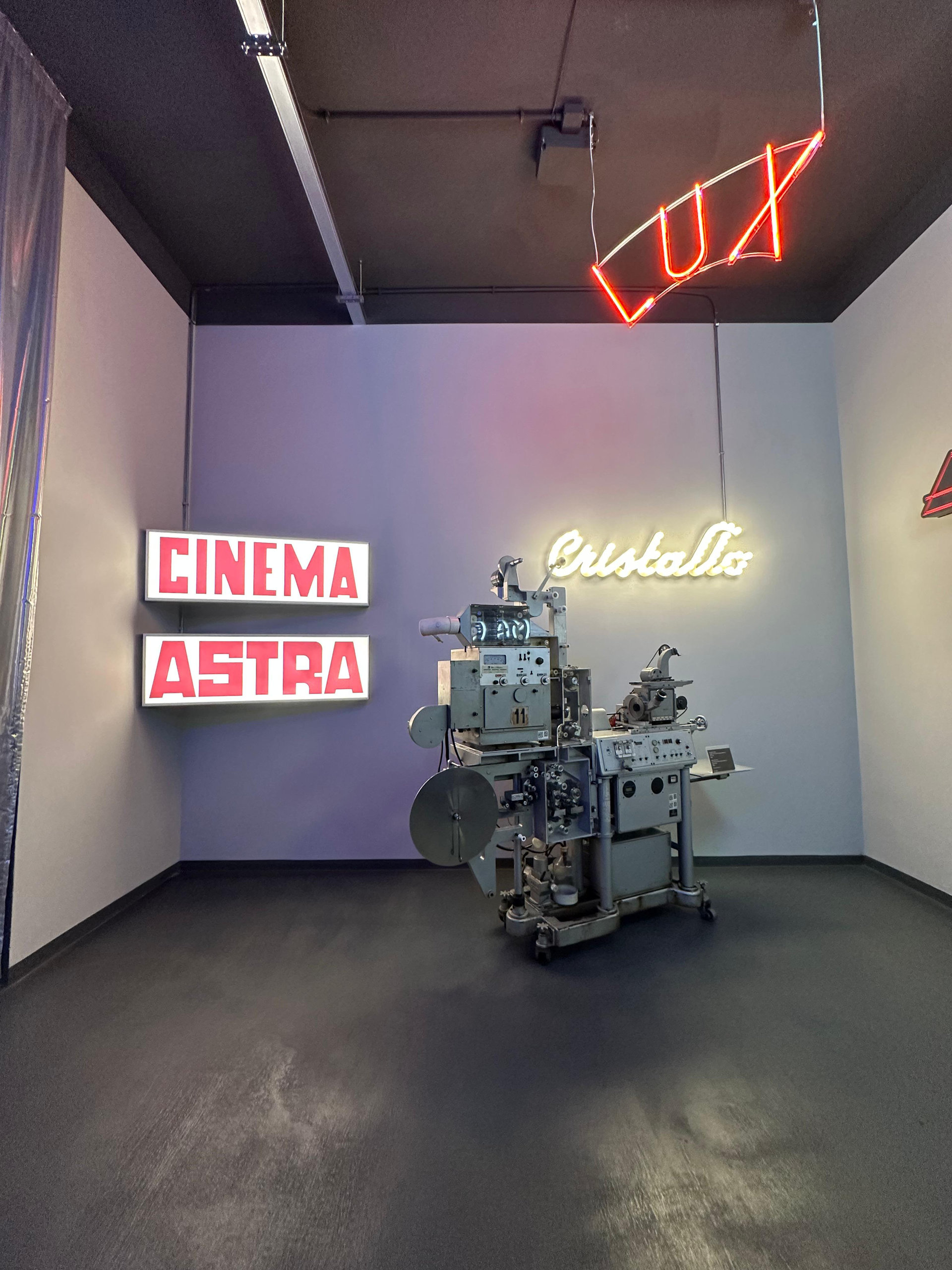 Neon cinema signs and a vintage projector in an exhibition room at MIAC