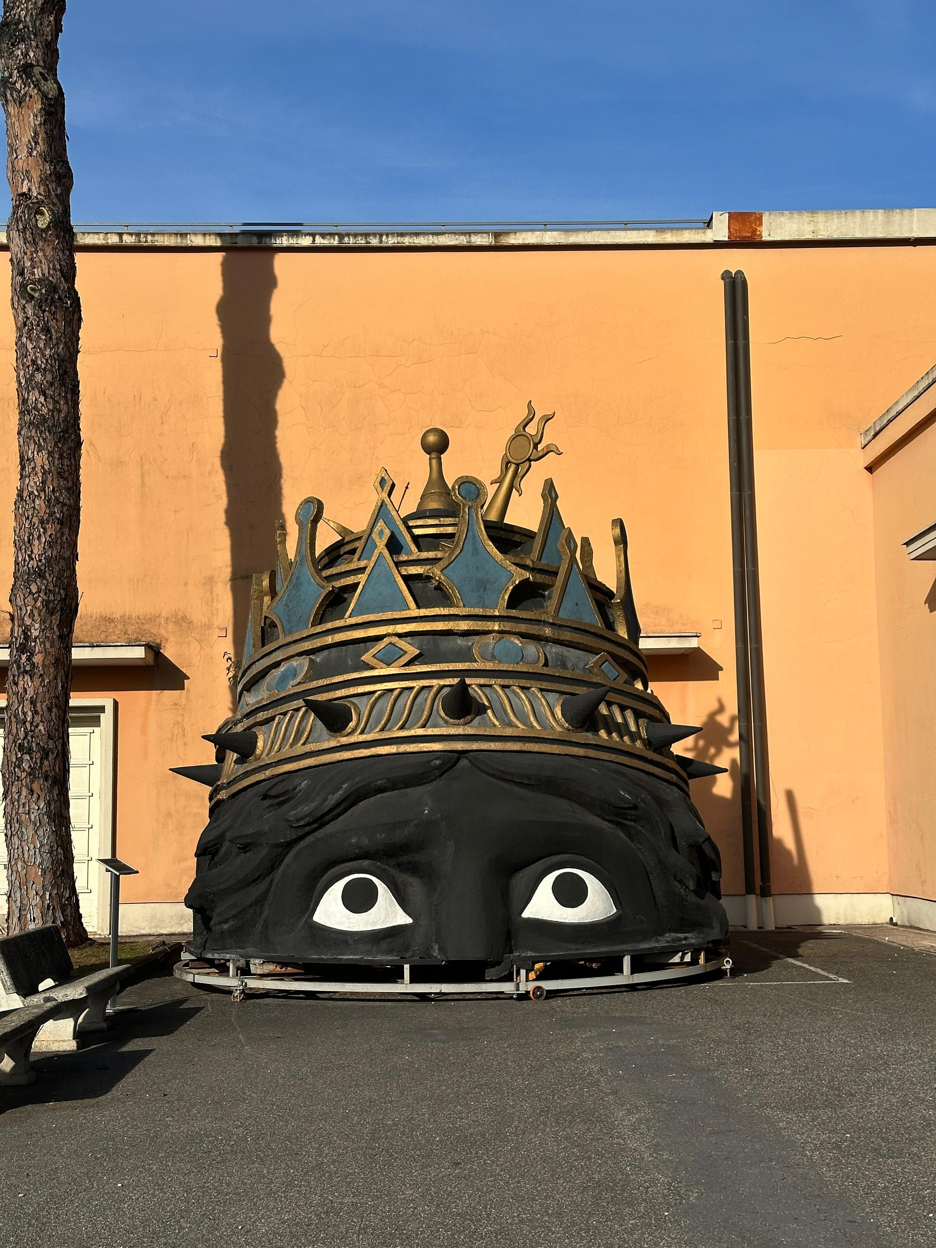 A giant crowned prop head from a film set standing in the Cinecittà backlot