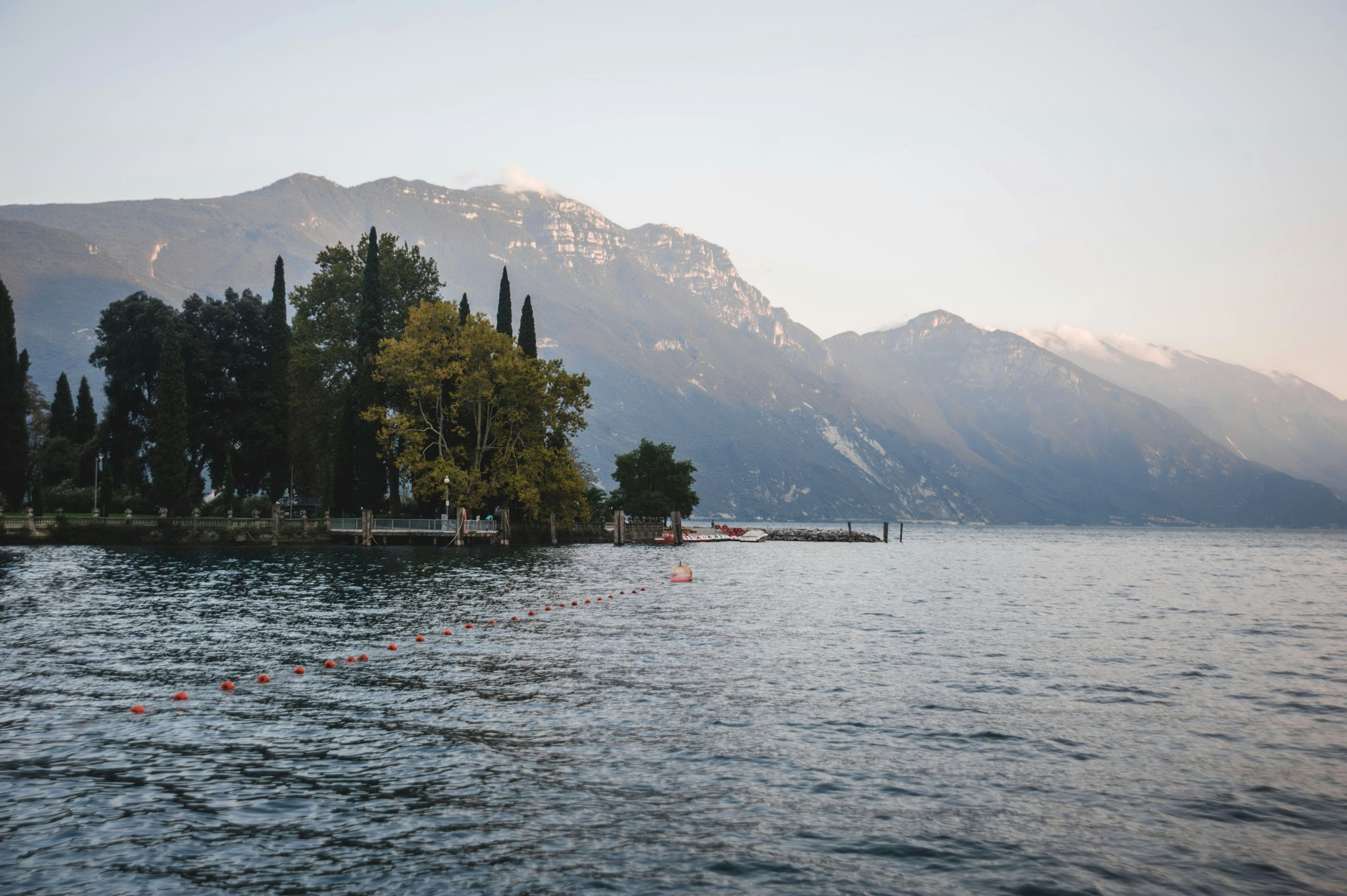 Lake Garda at dusk, a wooded promontory silhouetted against the mountains