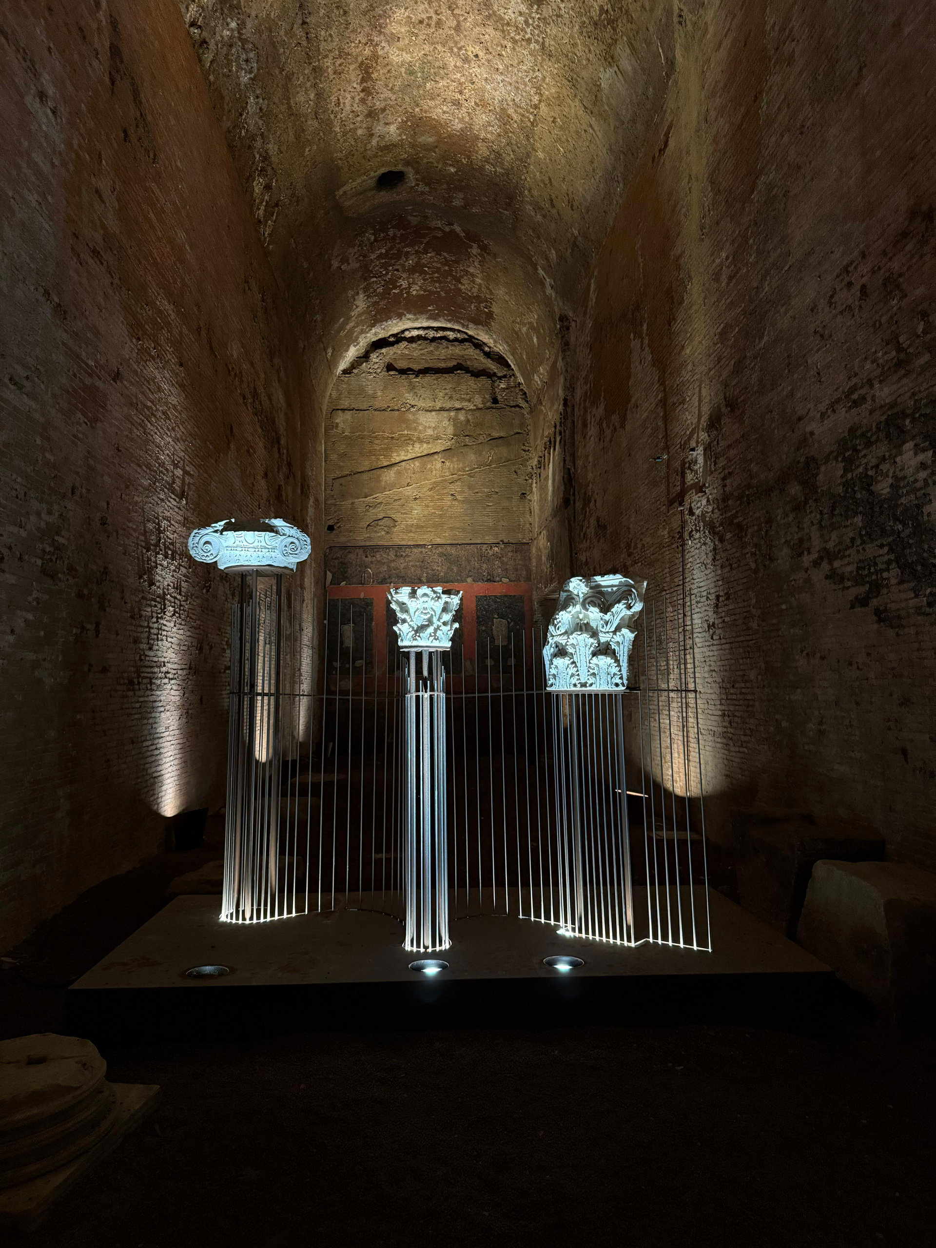 Lit columns of a modern installation inside a vaulted hall of the Domus Aurea