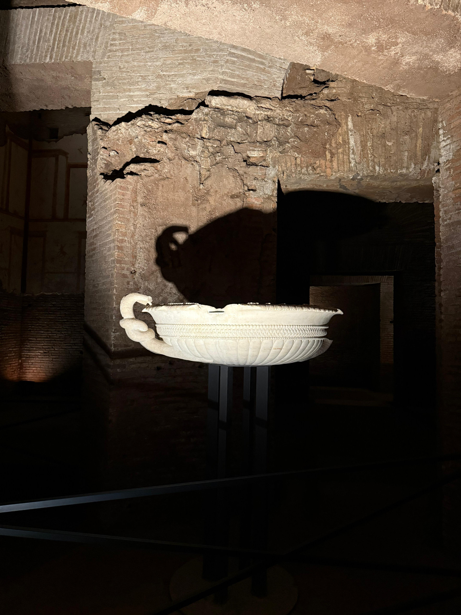 A white marble basin displayed in a brick-vaulted room of the Domus Aurea