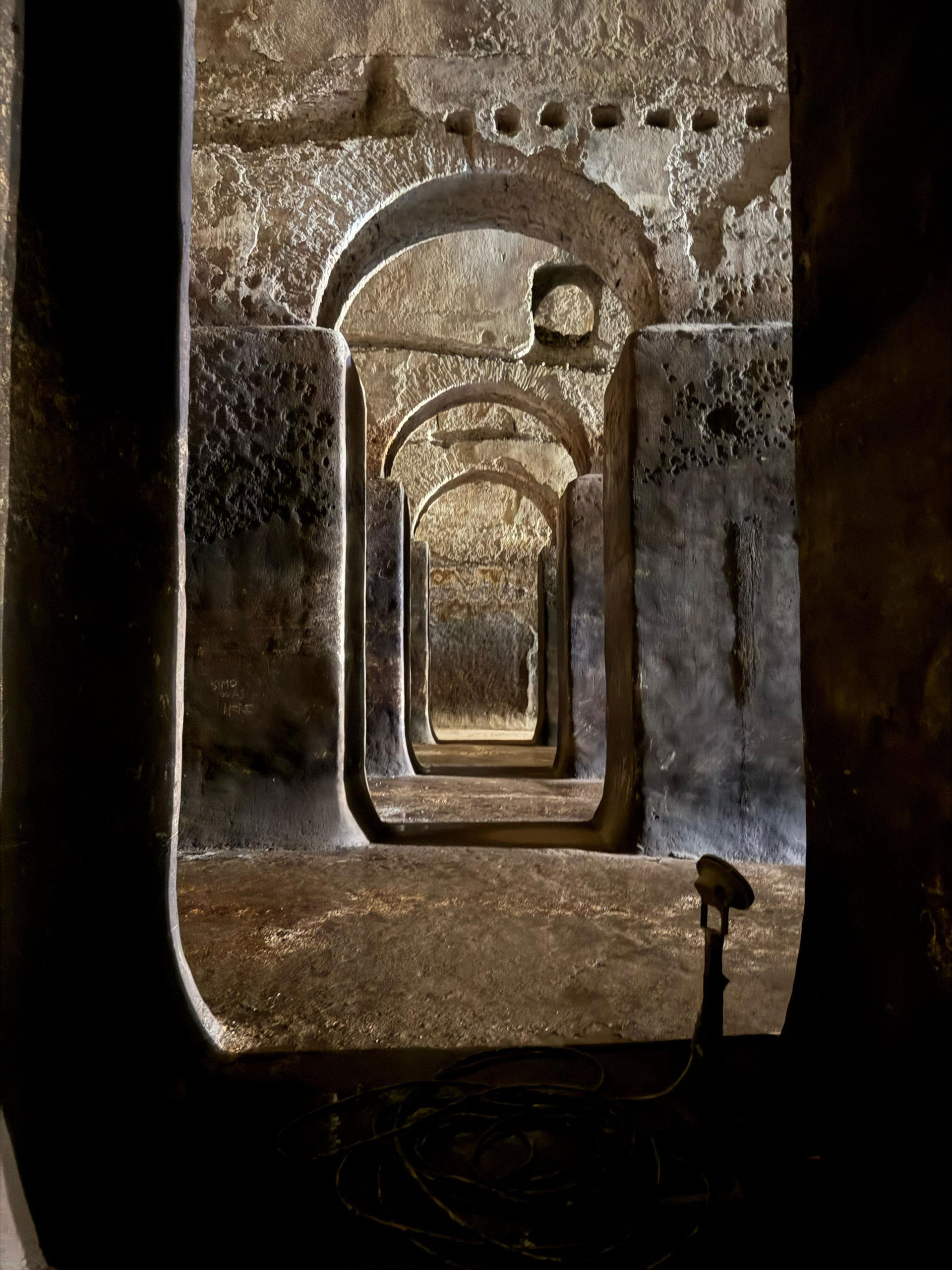 A carved stone niche lit in the half-dark of a Roman interior