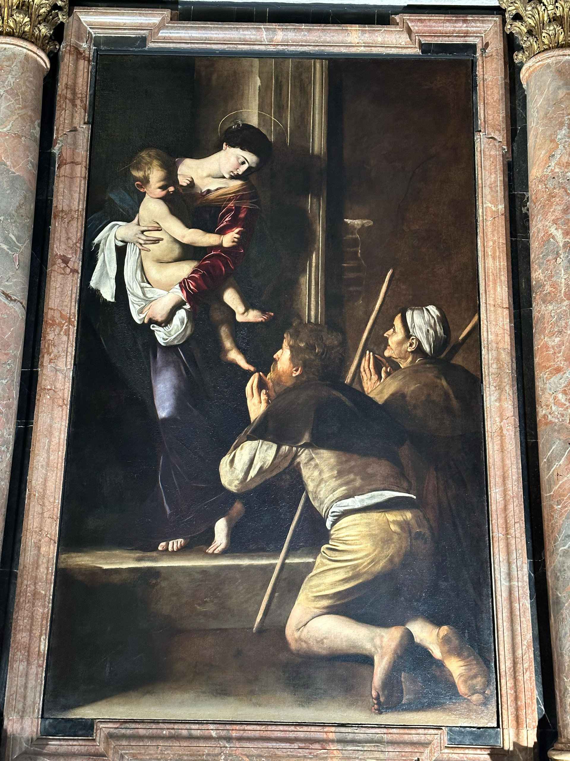 Caravaggio's Madonna of the Pilgrims above its altar in a Roman church