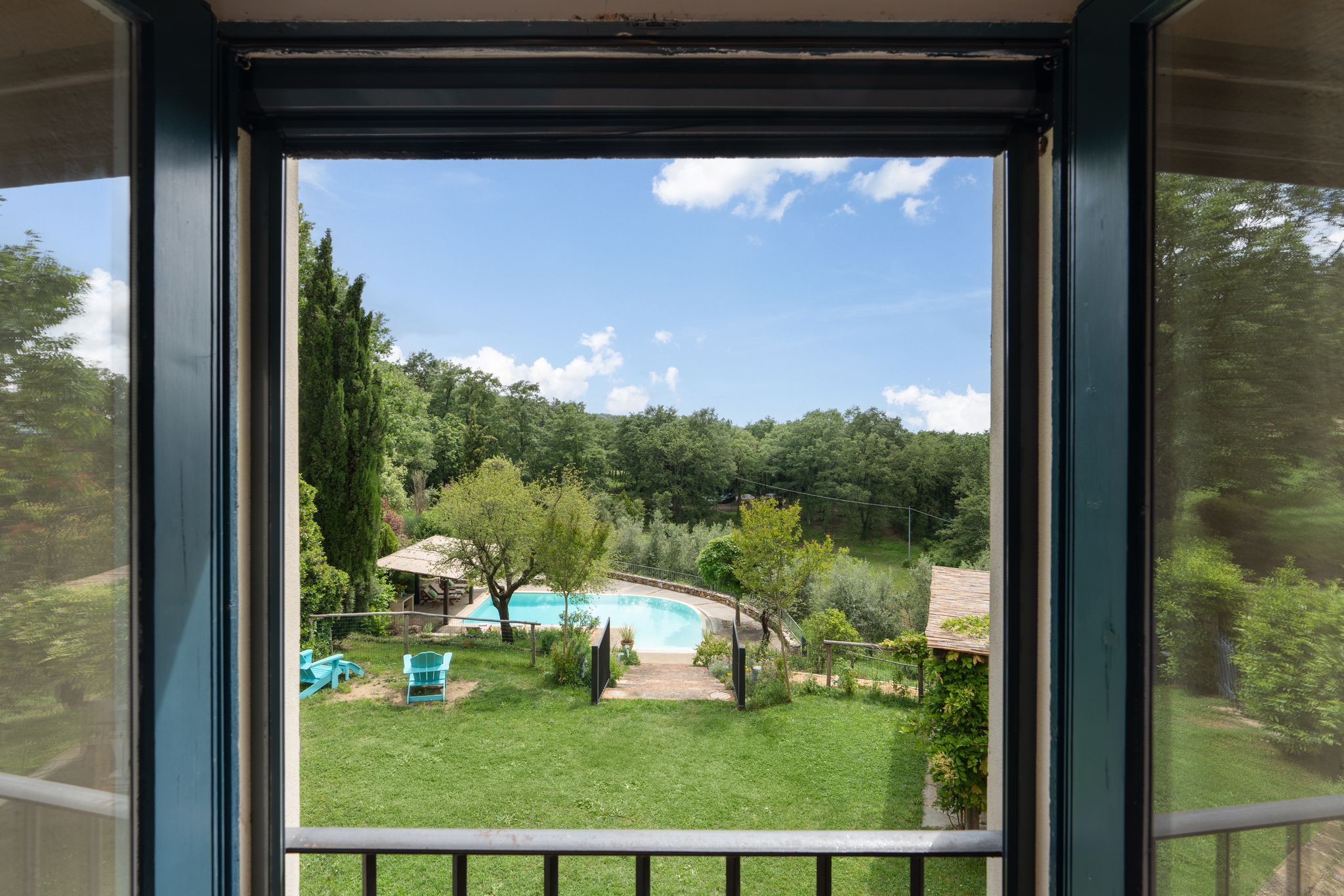 The garden and pool of the villa seen through an open window