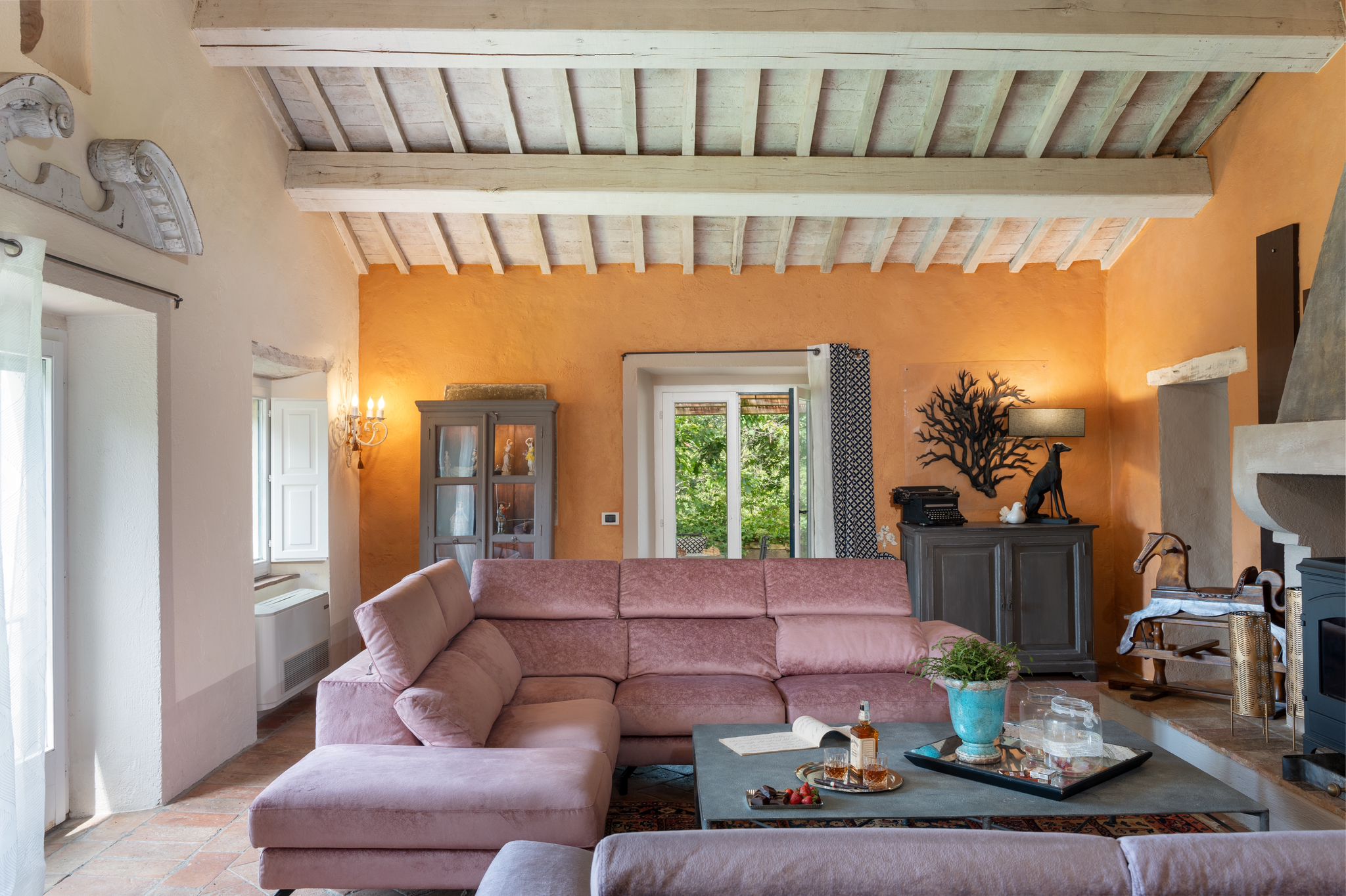 A living room with a beamed ceiling and pink sofas at the villa