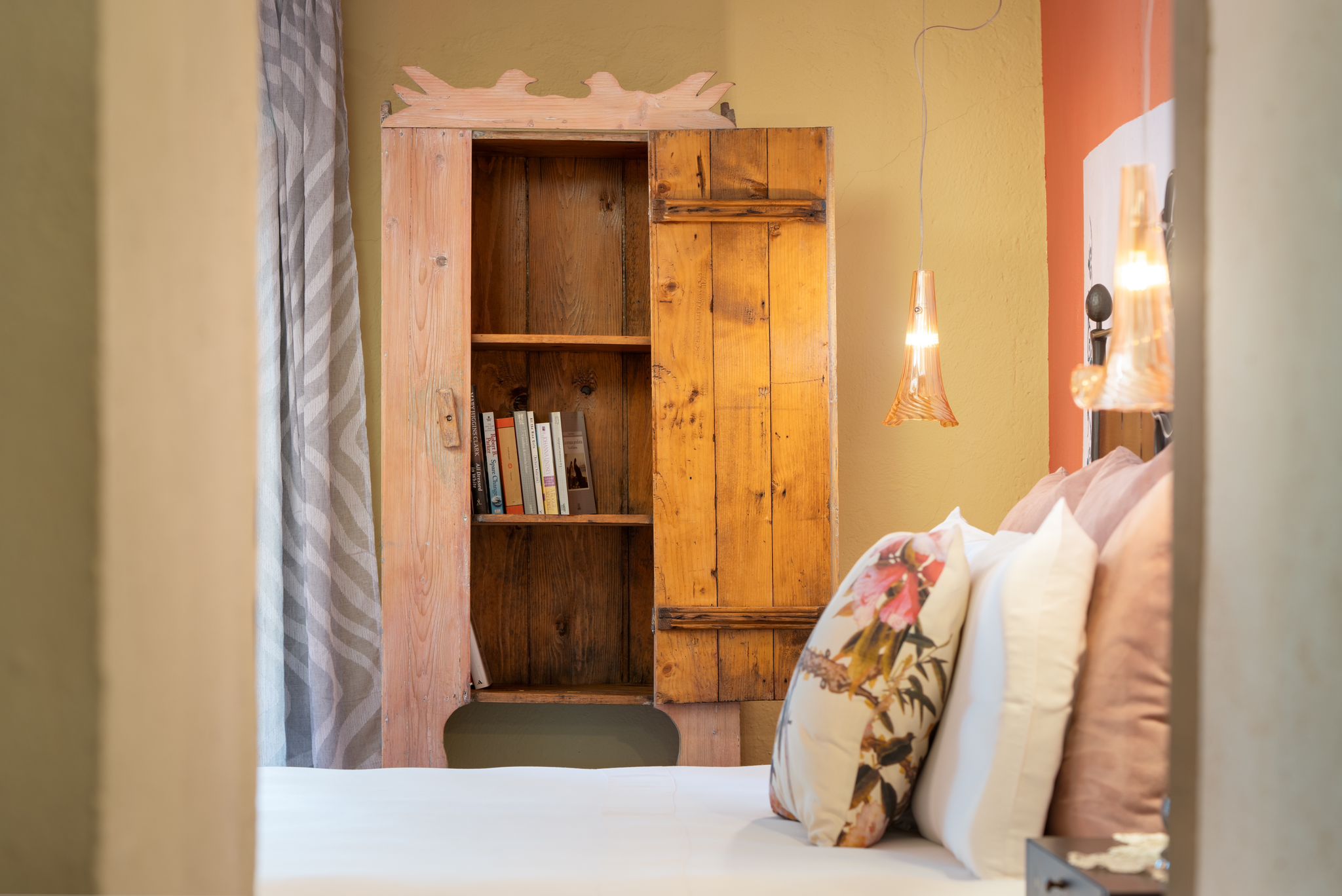 A bedroom with a wooden wardrobe and a cushioned bed at the villa