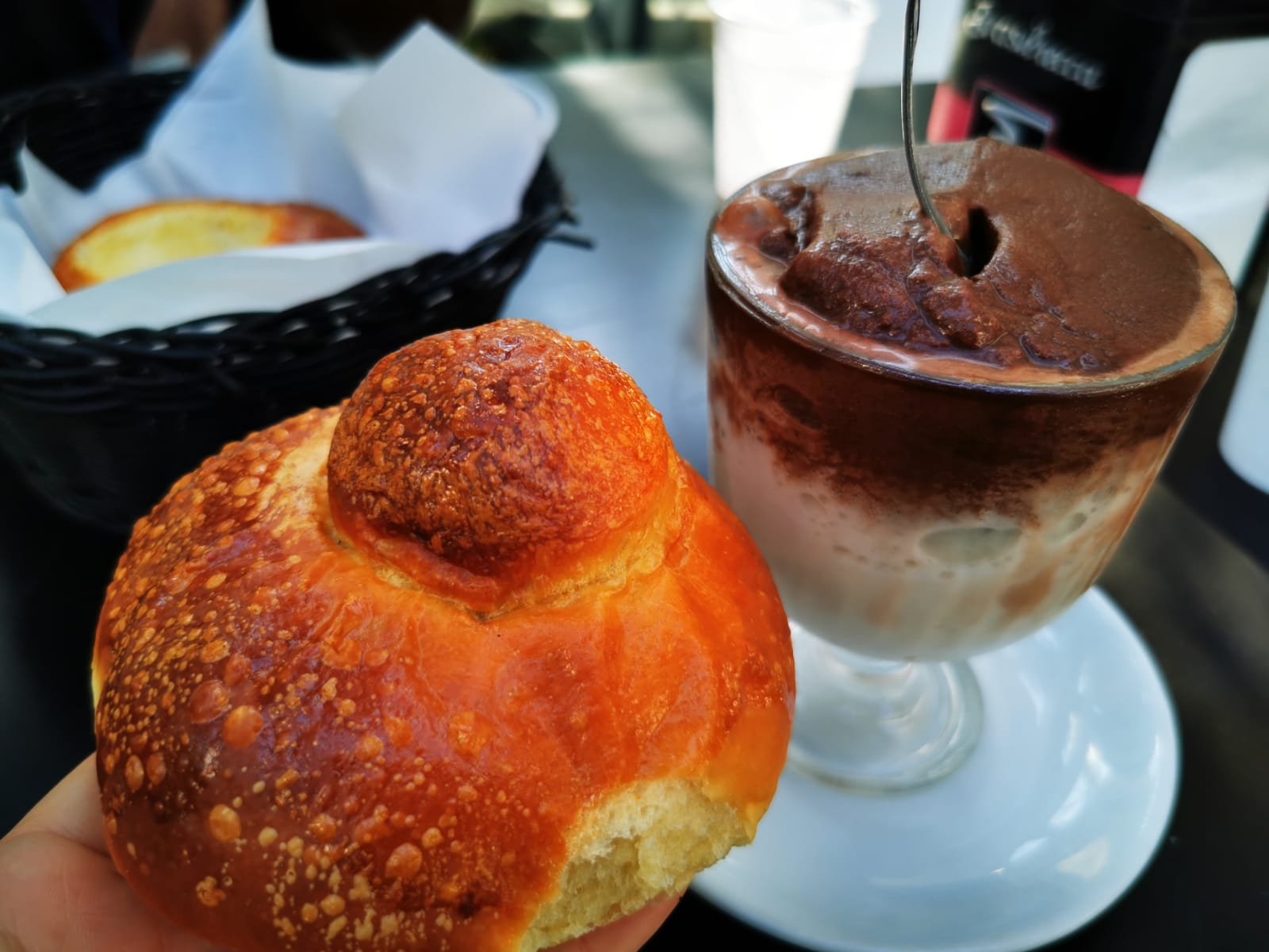 A cream-filled bun and an iced coffee dessert on a café table