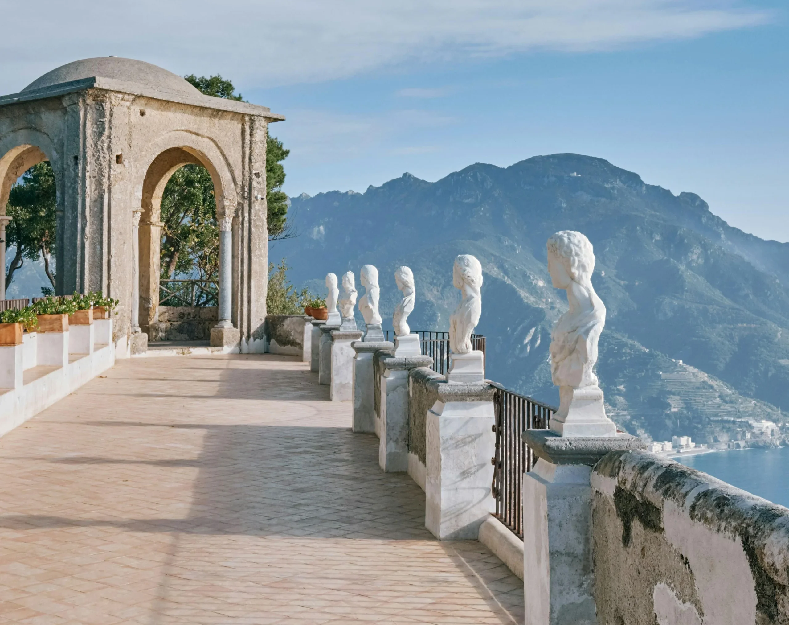 Terrace with a stone pavilion and marble busts lining the balustrade above the Amalfi Coast