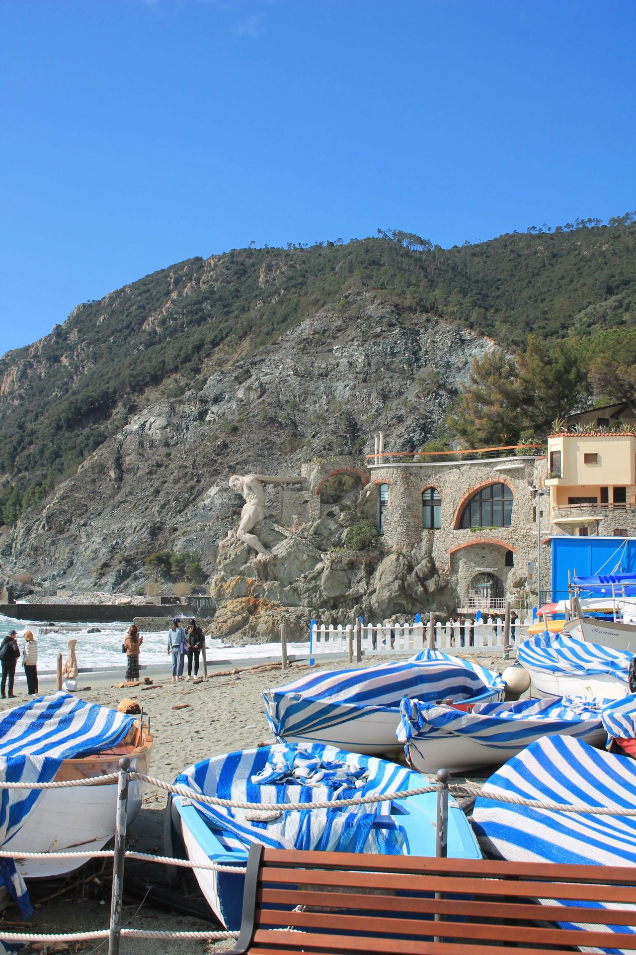 Striped beach umbrellas folded on a beach below a rocky headland