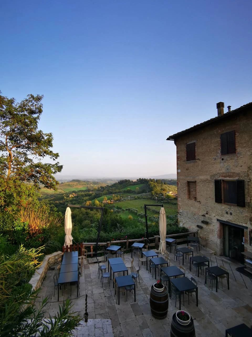 The terrace of a countryside farmhouse at dusk, tables set outside