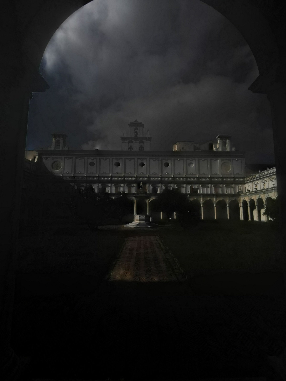 The cloister of a Naples monastery lit at night under a dark sky