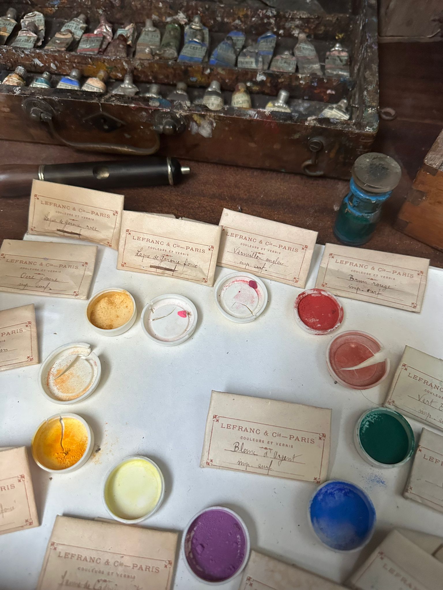 Old Lefranc Paris pigment pots and handwritten labels laid out beside a box of used paint tubes