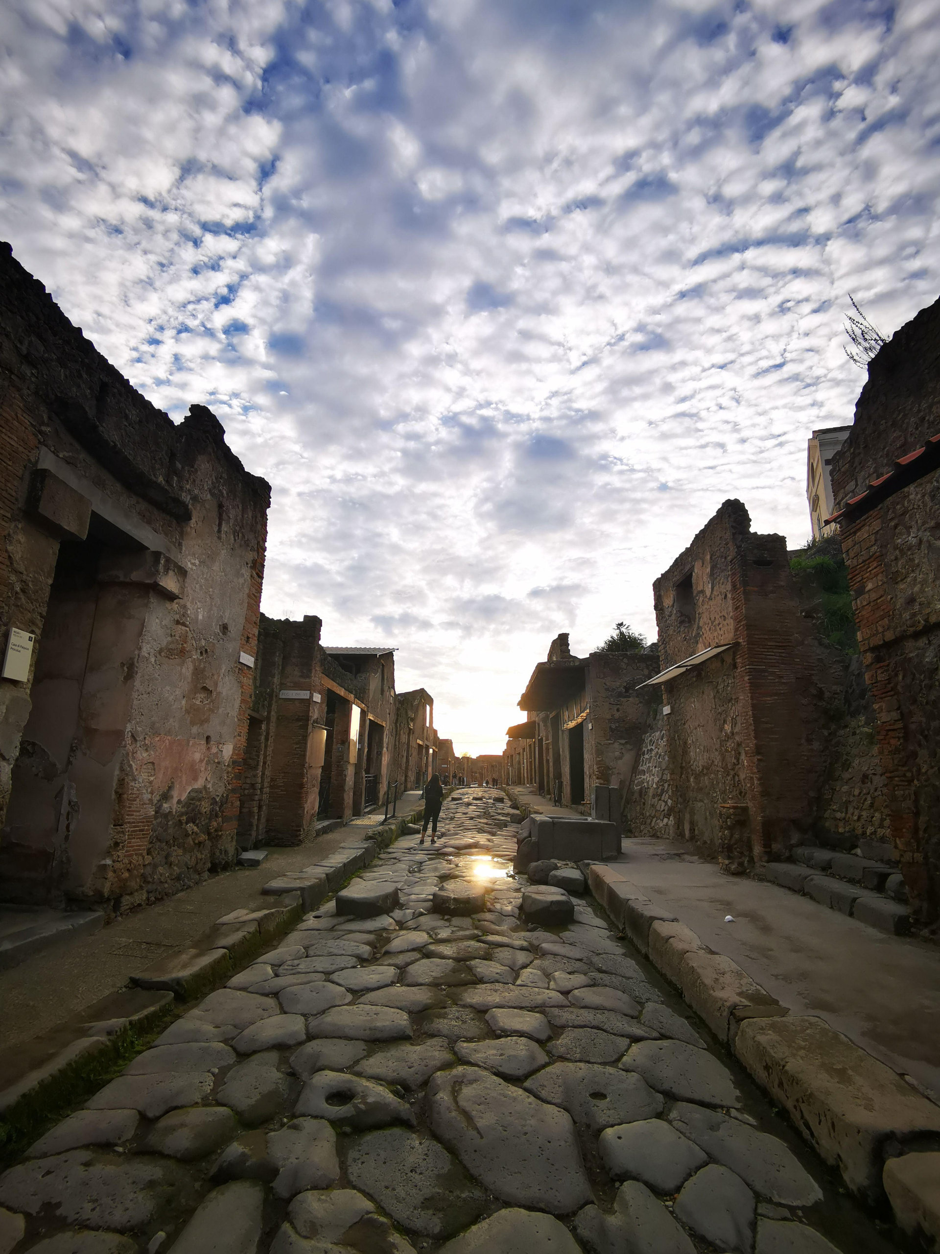 A paved Pompeian street at dawn between the ruined house fronts