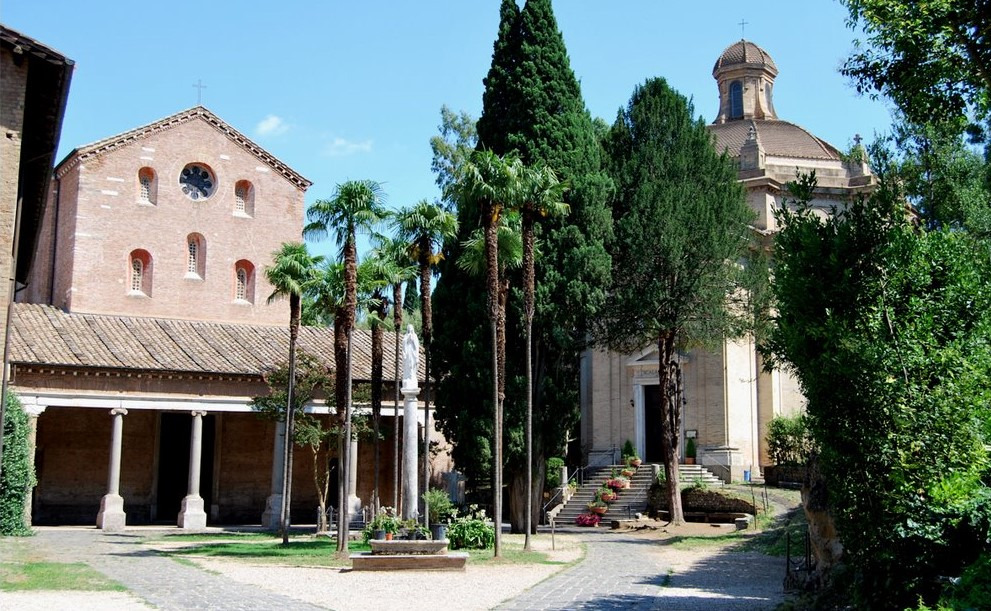 The courtyard of a Roman abbey, palm trees in front of the church