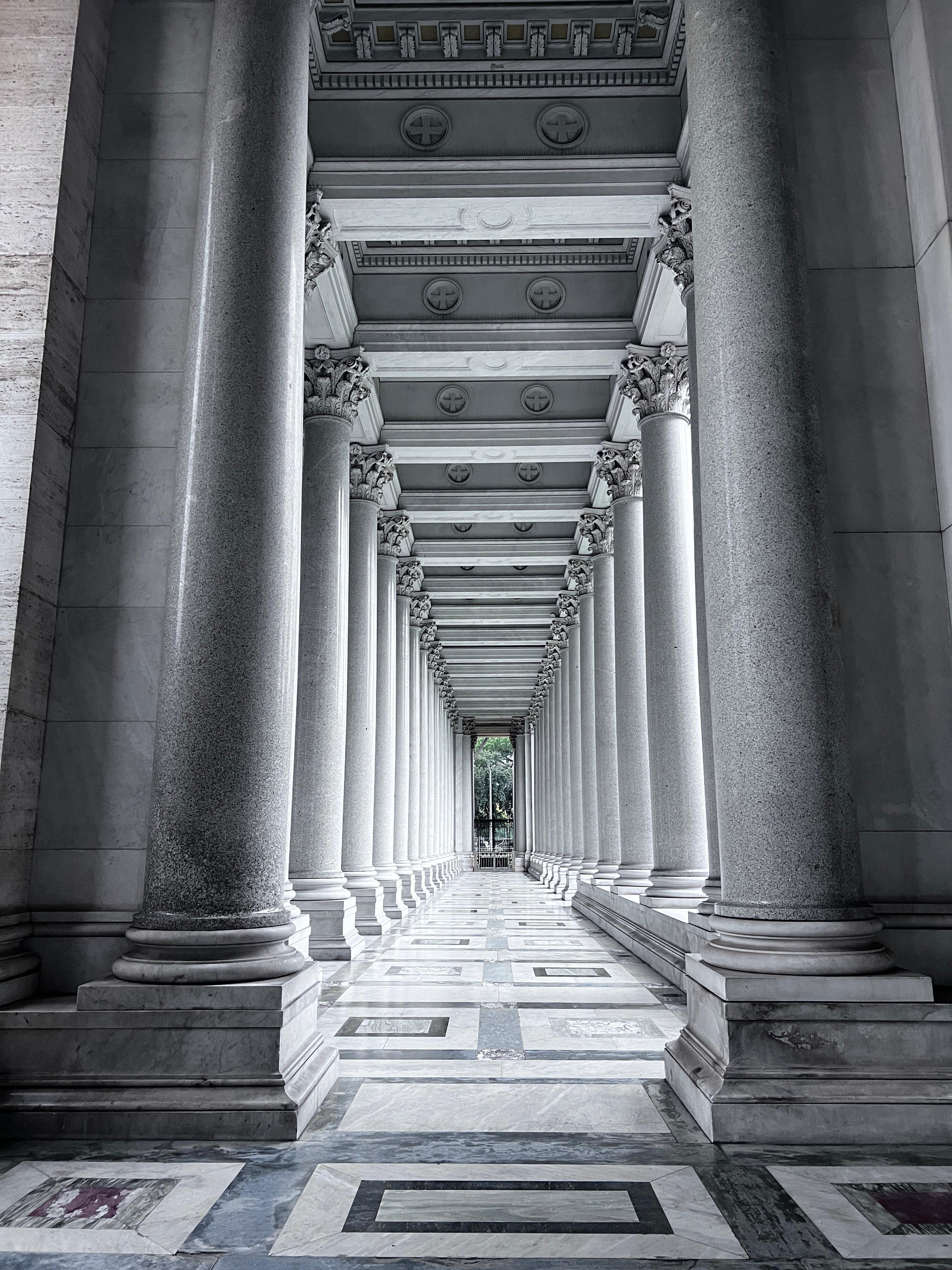 The basilica's colonnade in black and white, receding into the distance
