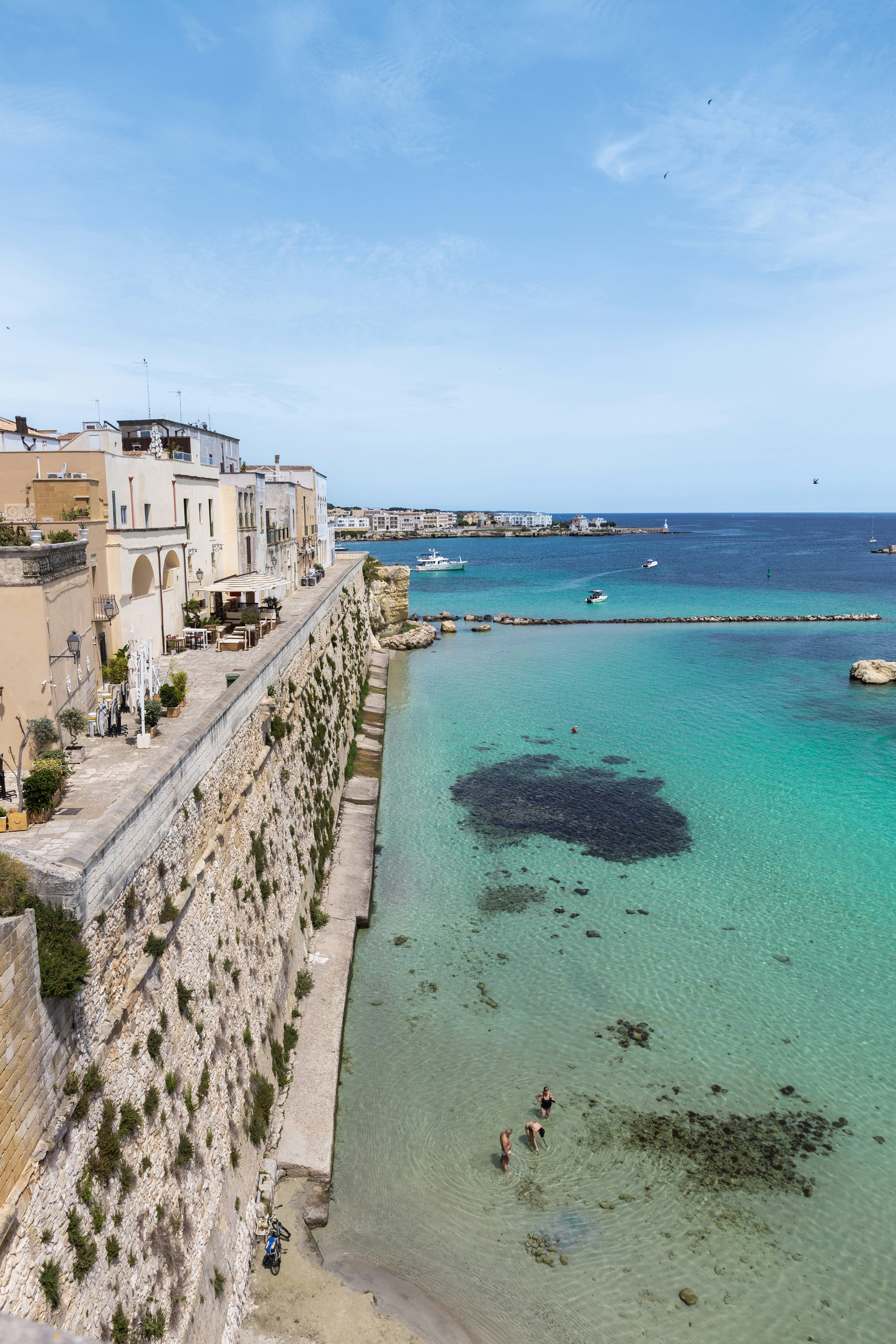 A turquoise bay below the walls of a town on the Puglia coast