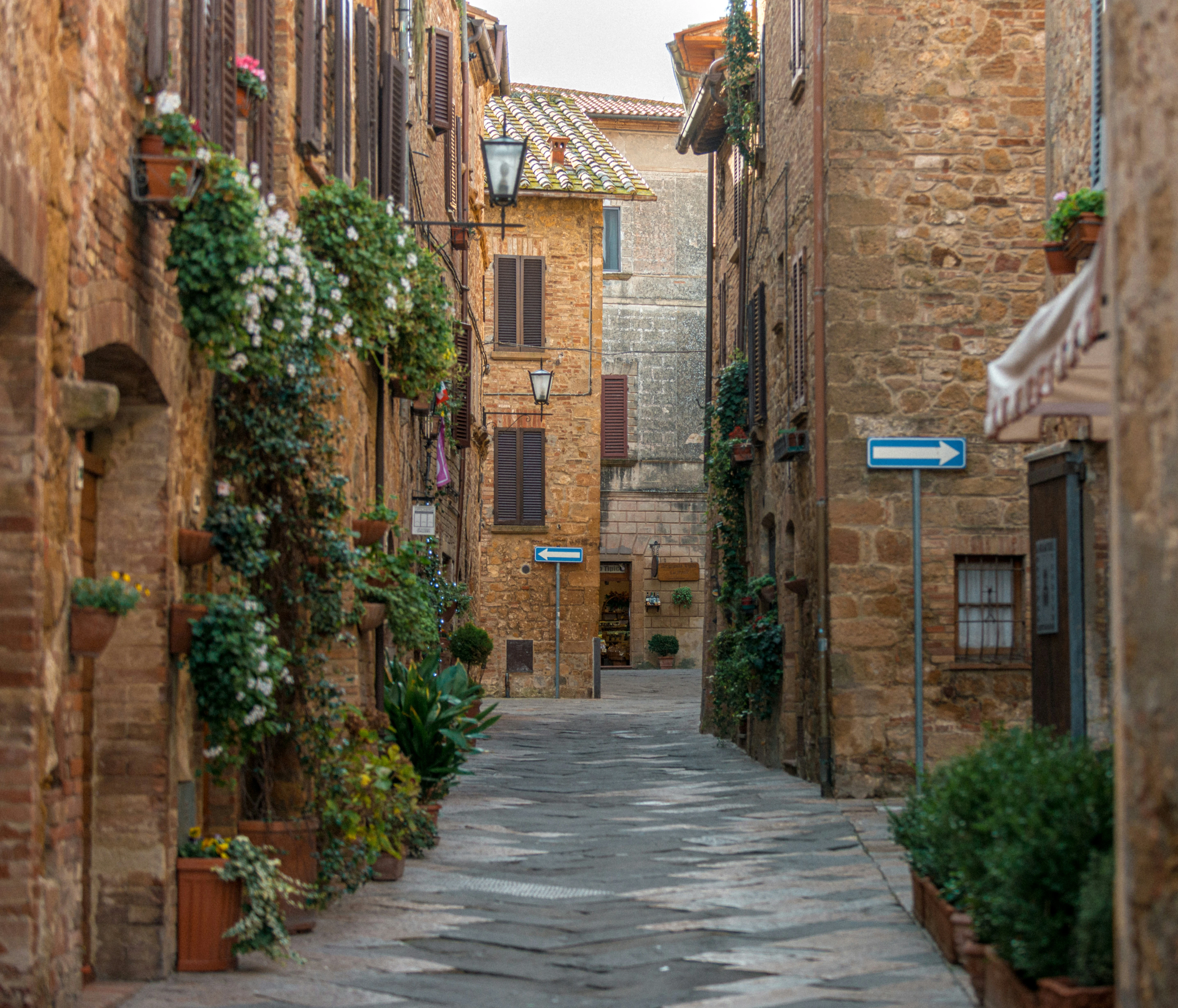 A stone street with flowered balconies in a Val d'Orcia village