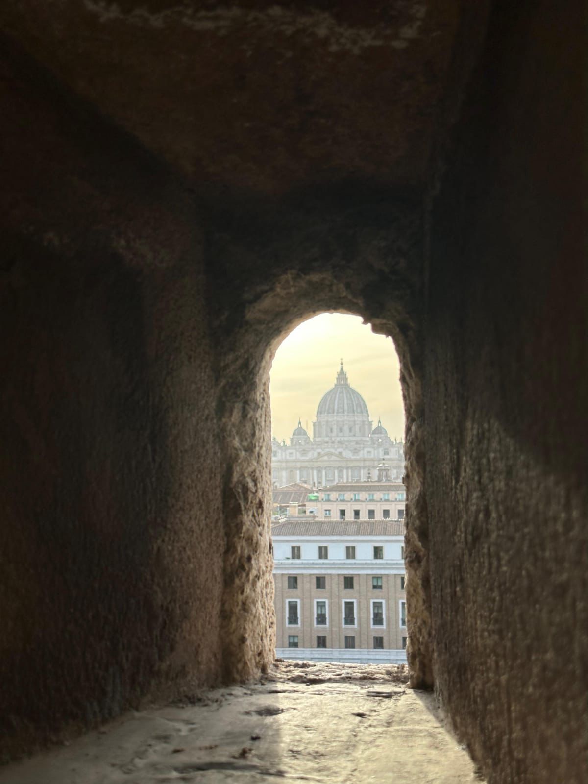 The dome of Saint Peter's framed at the end of a stone passage