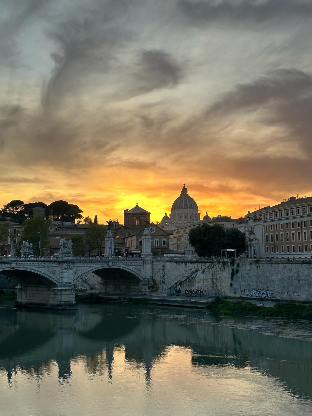 Sunset over the Tiber with a bridge and the dome of St Peter's silhouetted against a fiery sky