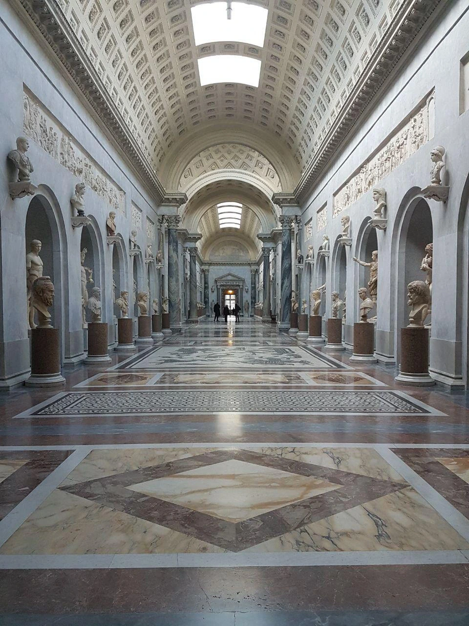 The empty marble gallery of the Vatican Museums, lined with ancient busts