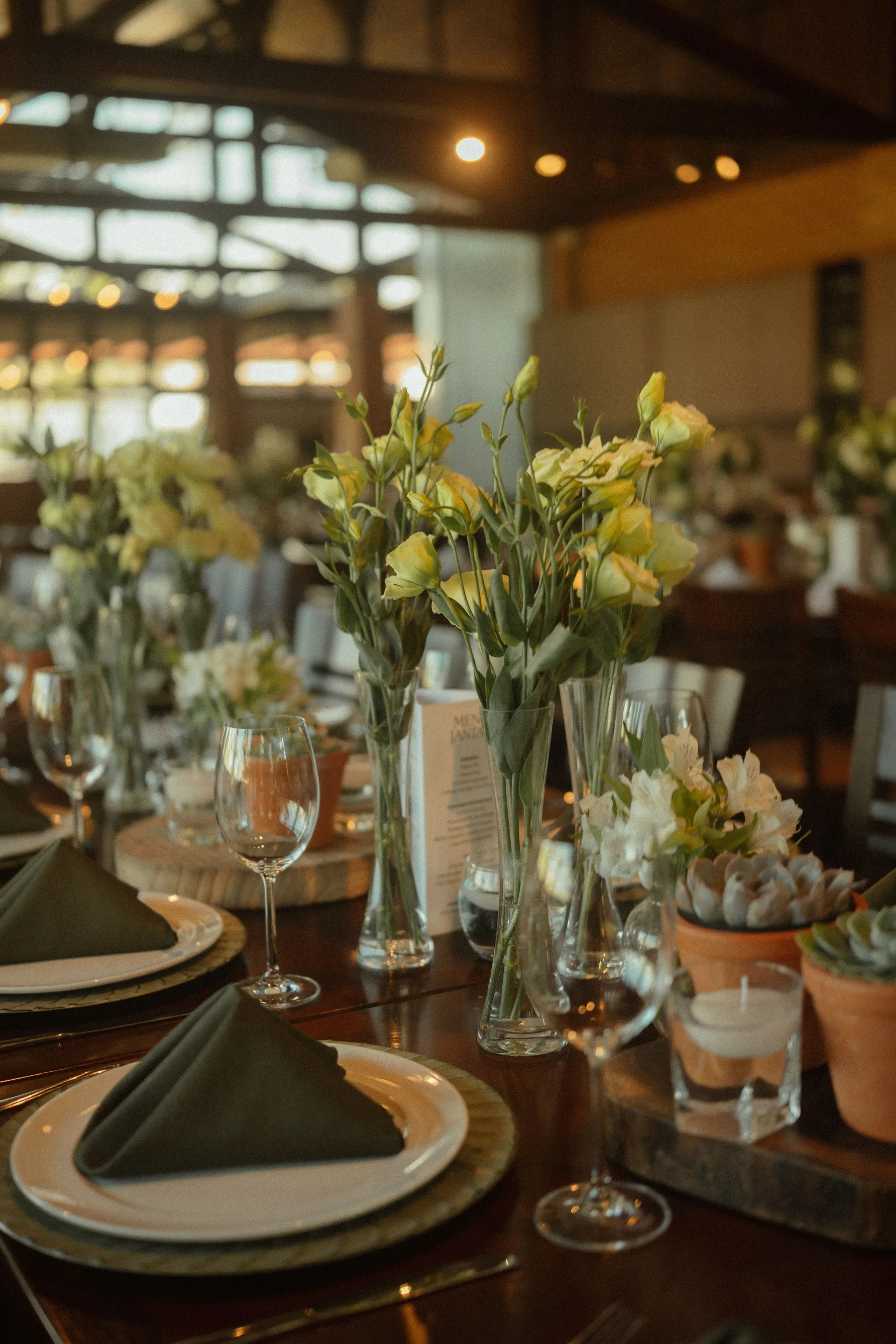 A long dinner table set with flowers, glasses and folded napkins for a group event