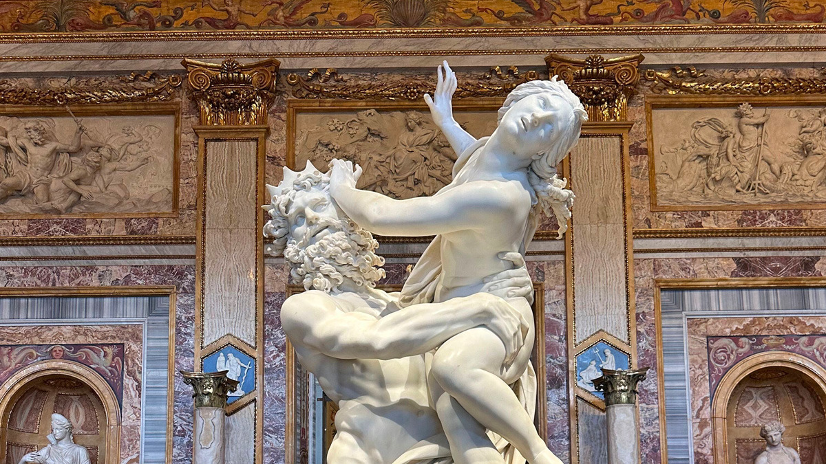 Baroque marble sculpture of a man seizing a struggling woman in a richly decorated gallery room