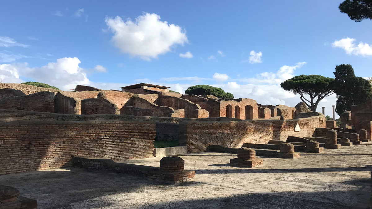 Ancient Roman brick ruins and umbrella pines under a bright sky at Ostia Antica