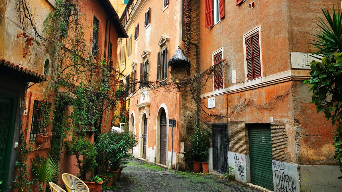Quiet Roman lane lined with ochre and terracotta houses, ivy and shuttered windows