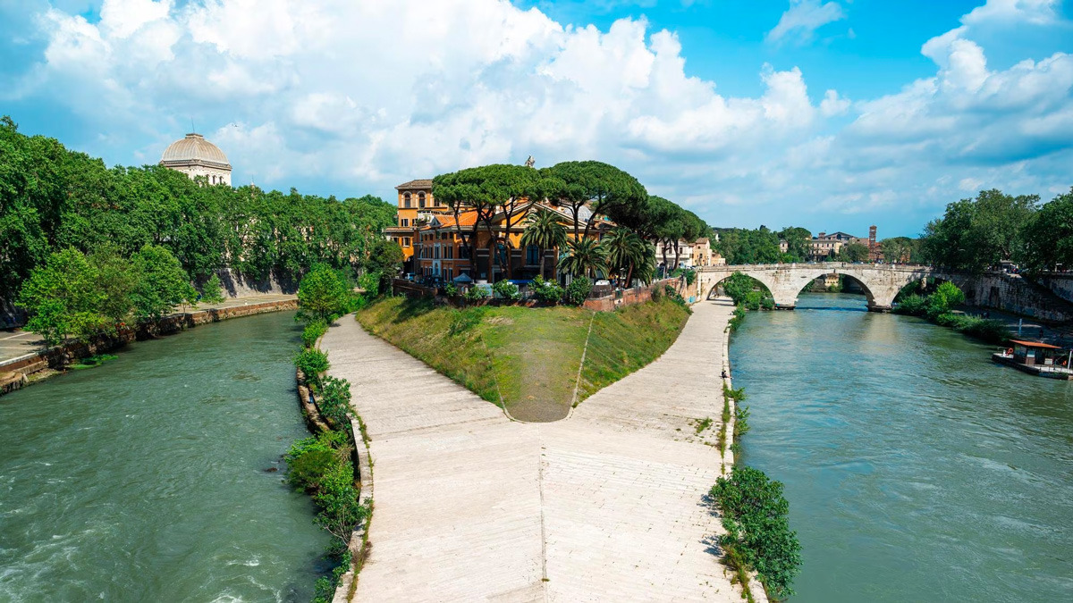 Tiber Island seen from above, with the river splitting around it and an ancient bridge beyond