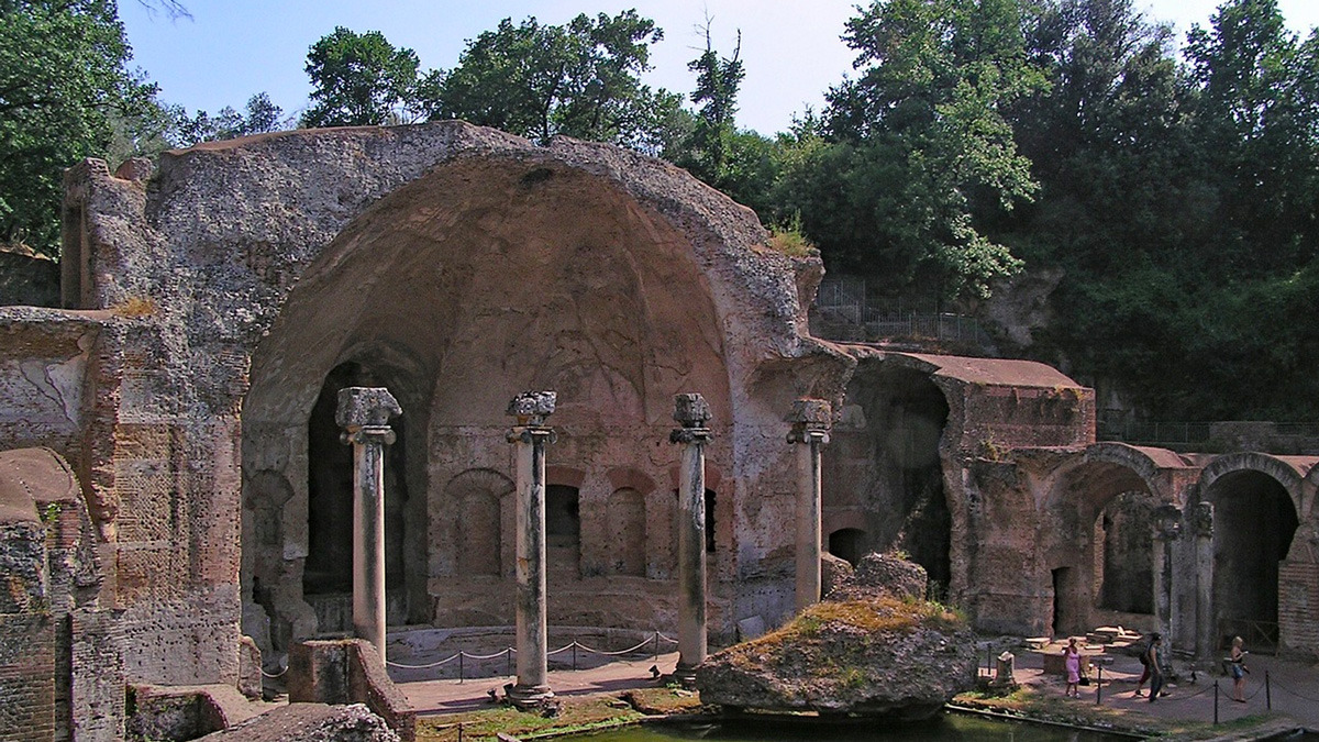 Vast ruined apse with tall arches and slender standing columns beside a water basin