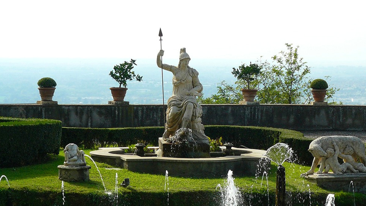 Marble statue holding a spear in a clipped garden with fountains and terracotta pots