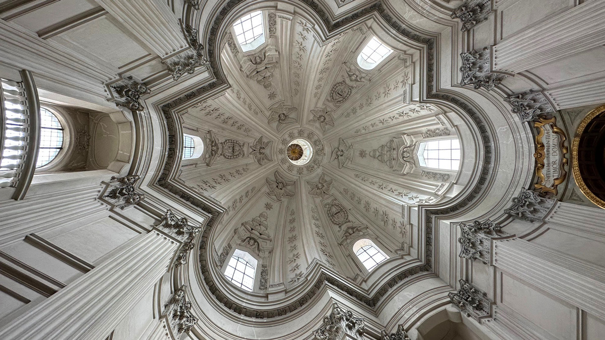 Elaborate star-patterned coffered dome of a Roman Baroque church seen from below