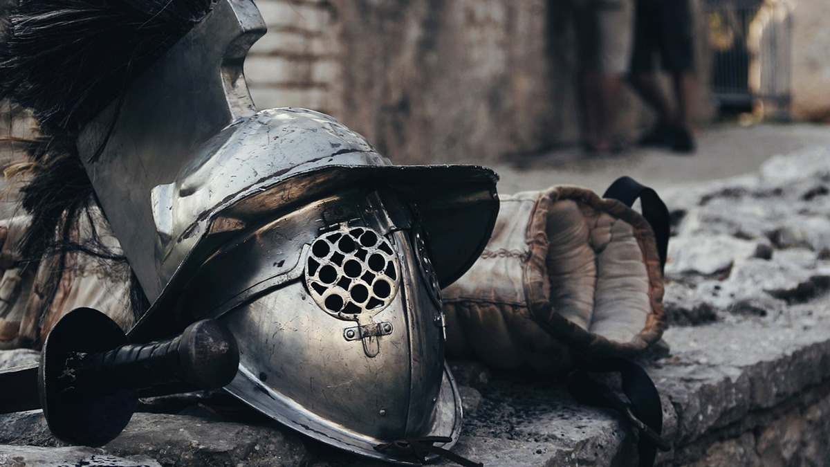 Gladiator helmet and arm guard resting on a weathered stone ledge