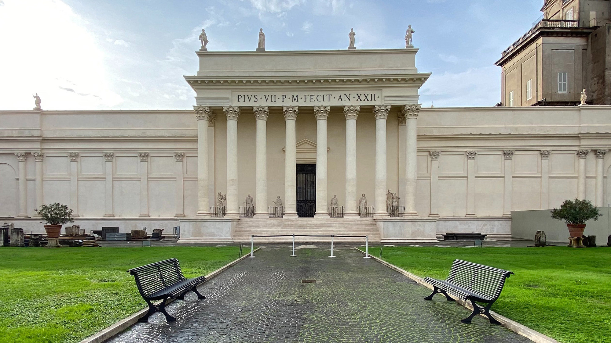 Neoclassical building with a columned portico facing a lawn and cobbled path in the Vatican Museums