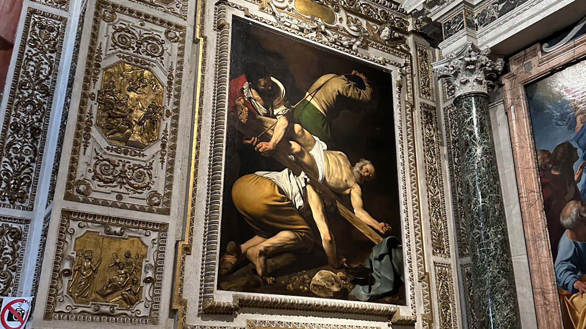 Caravaggio's Crucifixion of St Peter in its ornate frame in a side chapel