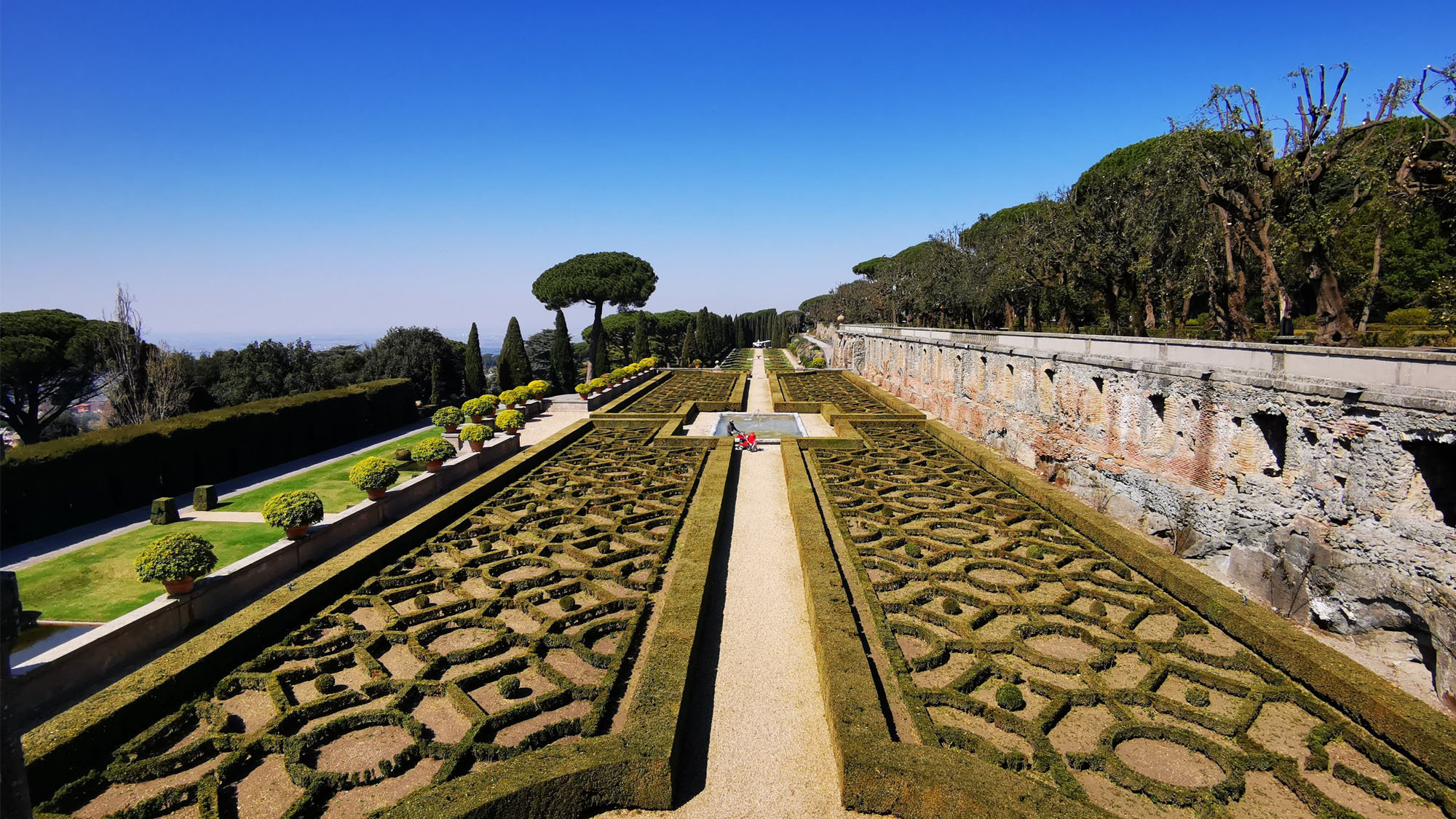 Intricate box-hedge parterres divided by a gravel path in a papal villa garden