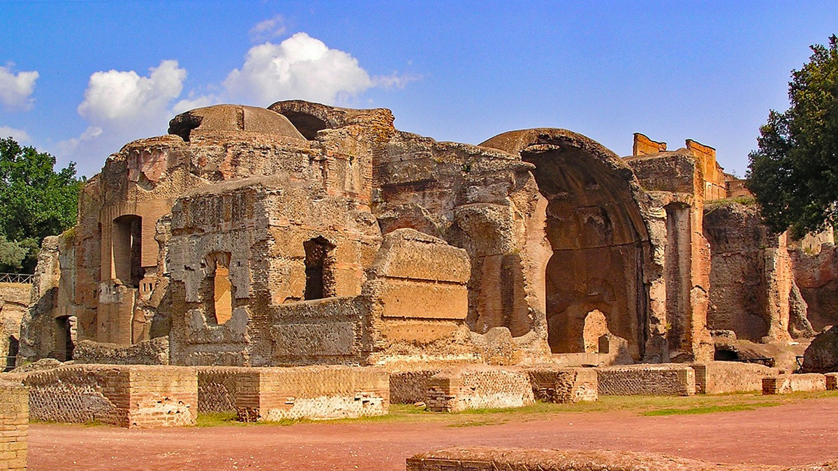 Ruined brick halls and vaults of an ancient Roman villa under a blue sky