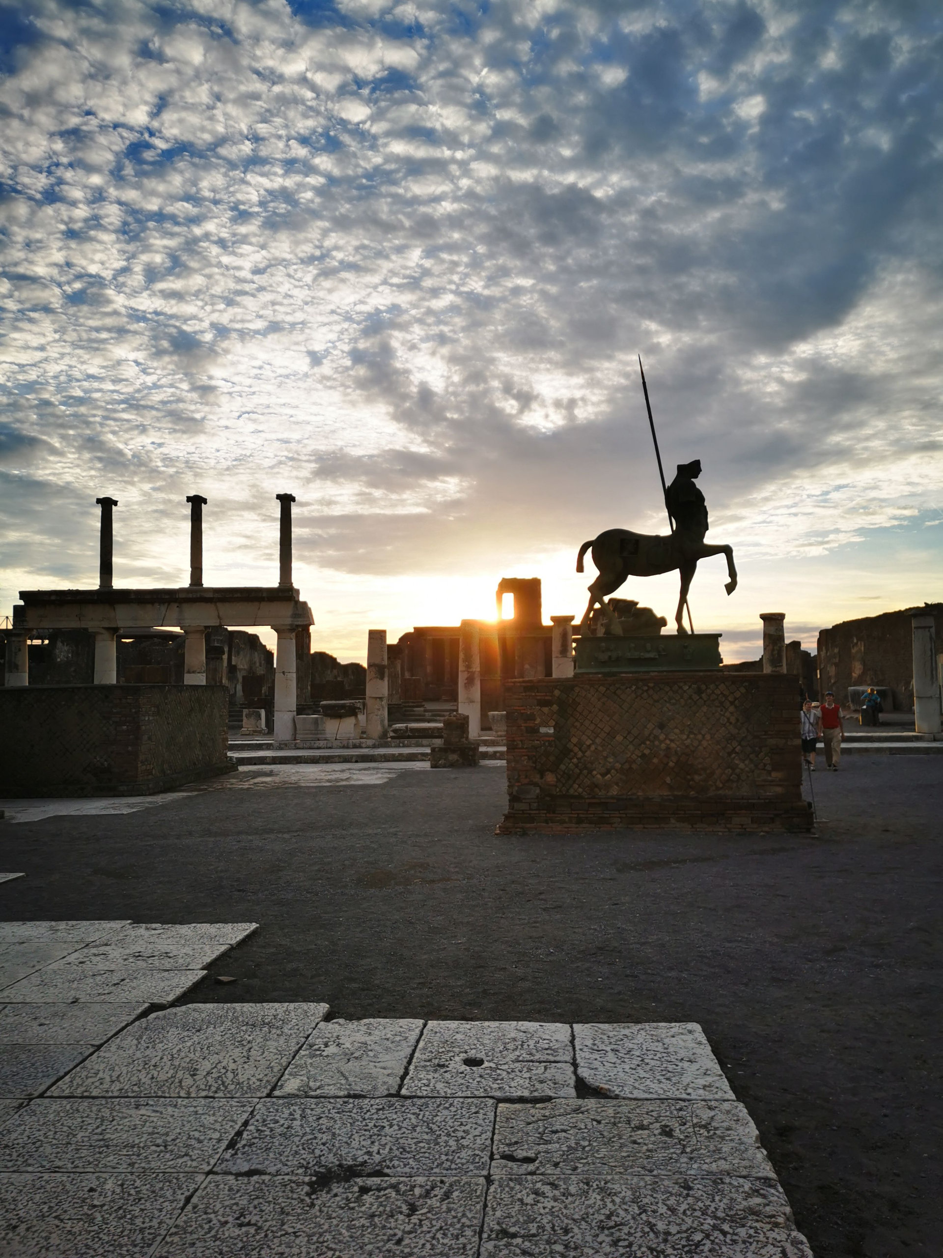 Statue of a centaur silhouetted against a sunset sky among the ruined columns of the forum