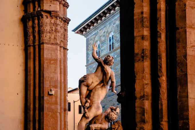 Marble sculpture group of a lifted figure in a Florentine loggia, framed by stone columns