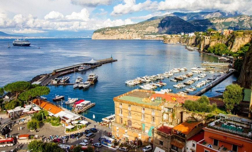 Sorrento marina with moored boats below the cliffs and a cruise ship in the bay