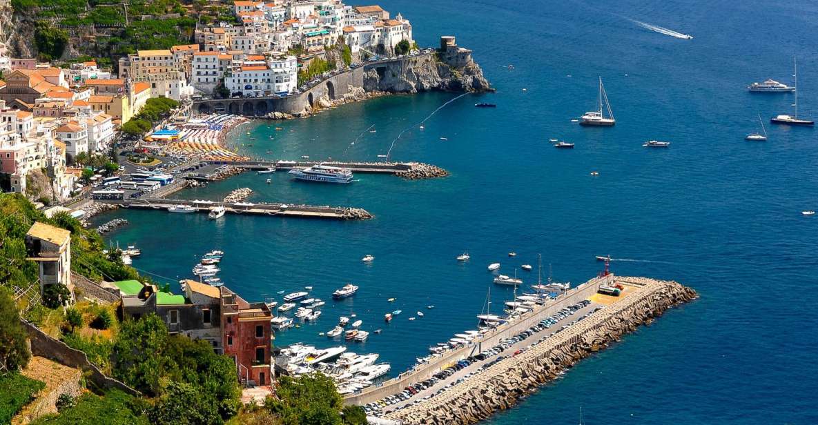 Aerial view of Amalfi's harbour with boats, a breakwater and a beach below the cliffs