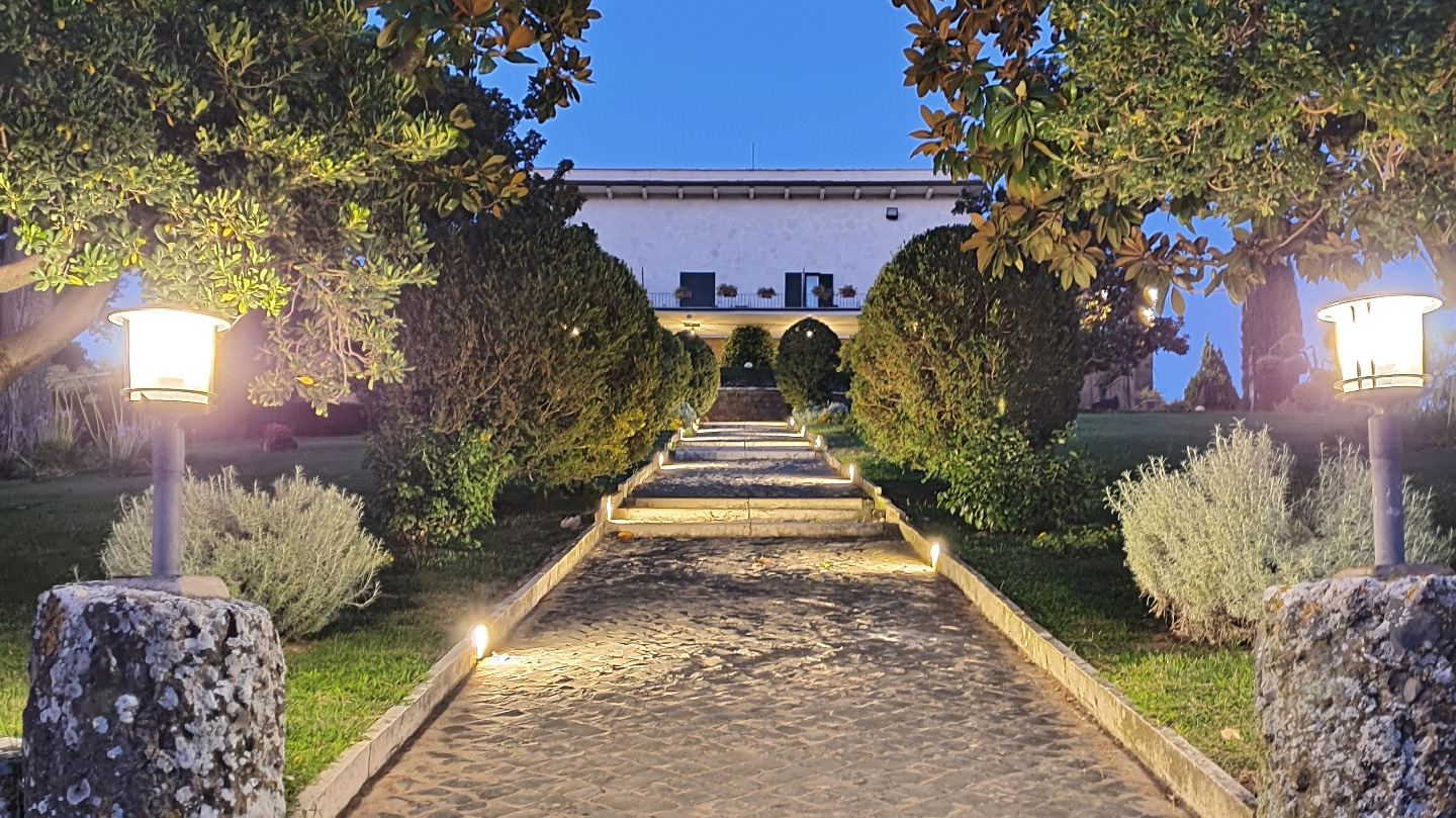 Winery villa at dusk at the end of a lantern-lit stone path lined with clipped shrubs