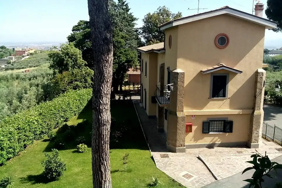 Ochre country house on a hillside with a lawn, olive trees and distant views