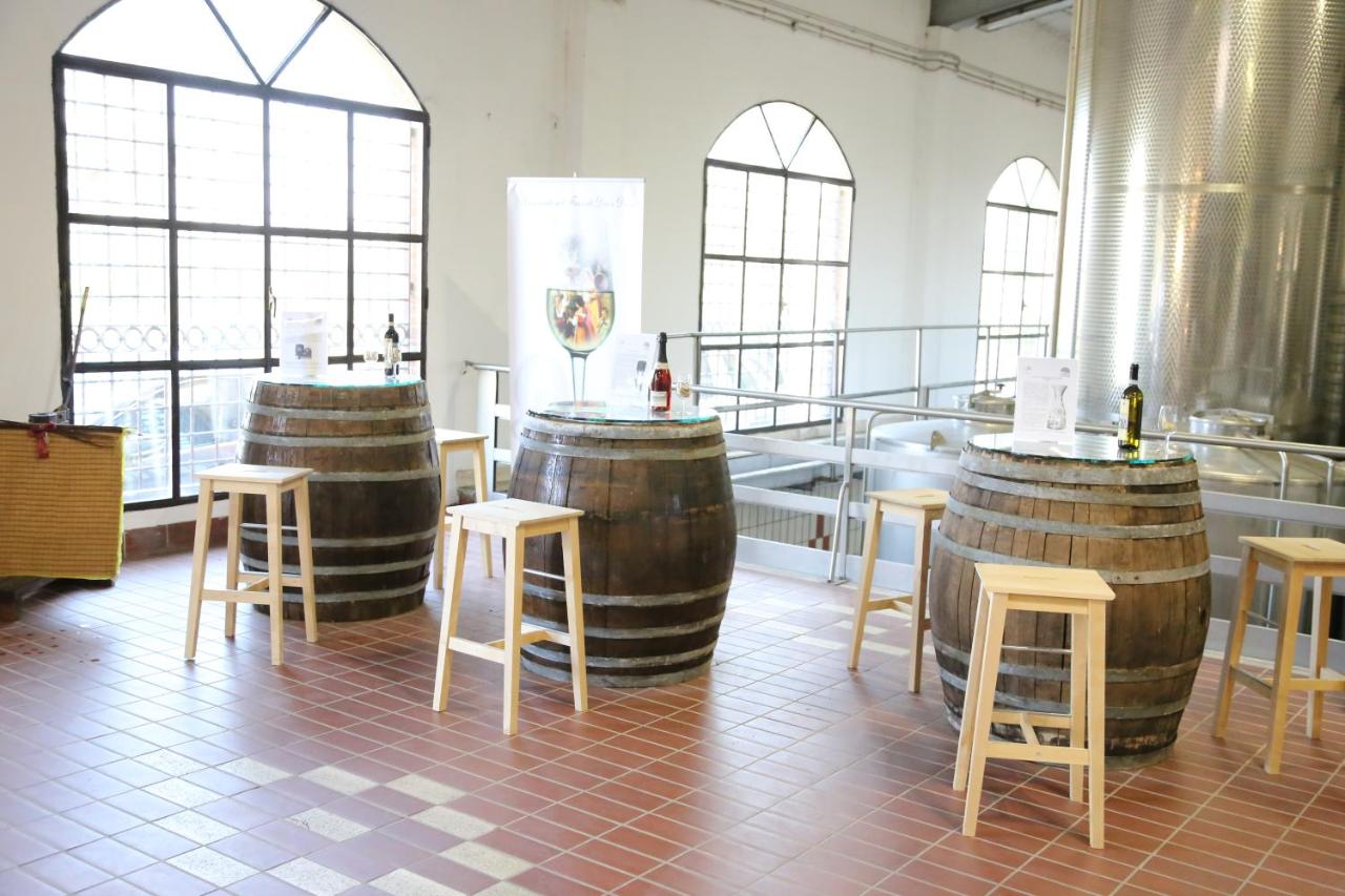 Wine tasting area with barrel tables, wooden stools and steel fermentation tanks in a bright hall