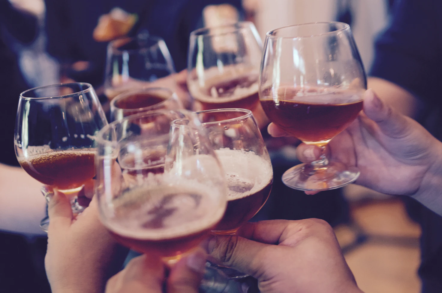 Hands raising glasses of amber beer for a toast
