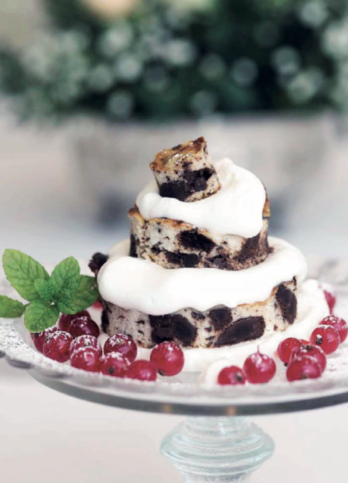 Layered chocolate cake dessert with cream and red currants on a glass cake stand