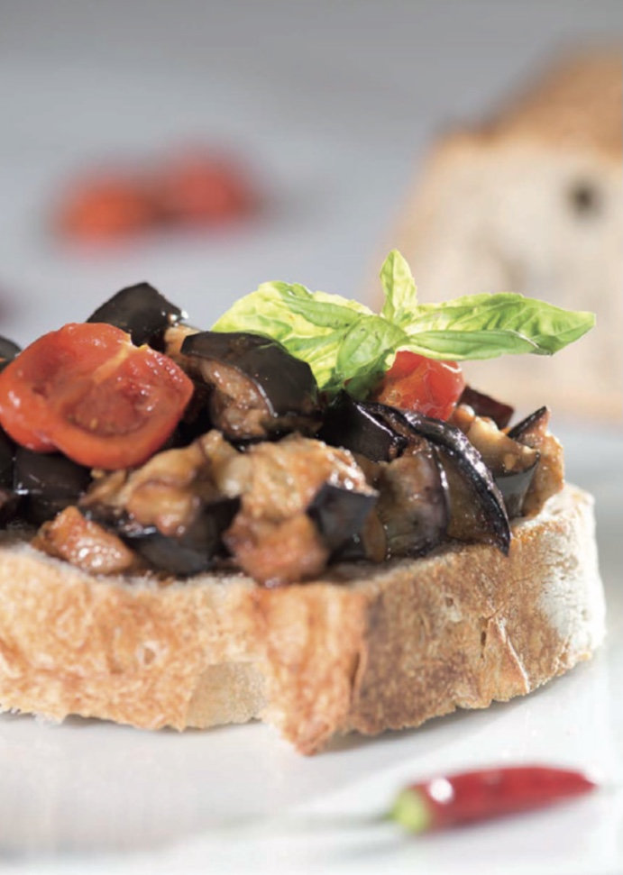 Toasted bread topped with sautéed aubergine, cherry tomatoes and a fresh basil leaf