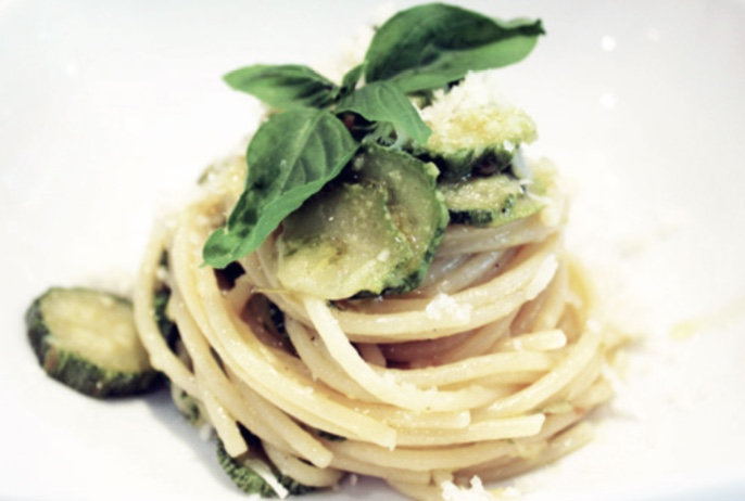 Spaghetti twirled into a nest with courgette slices, basil and grated cheese